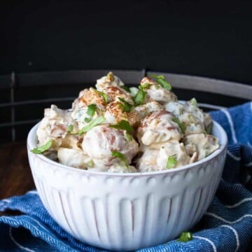 White bowl filled with creamy potato salad on a blue napkin