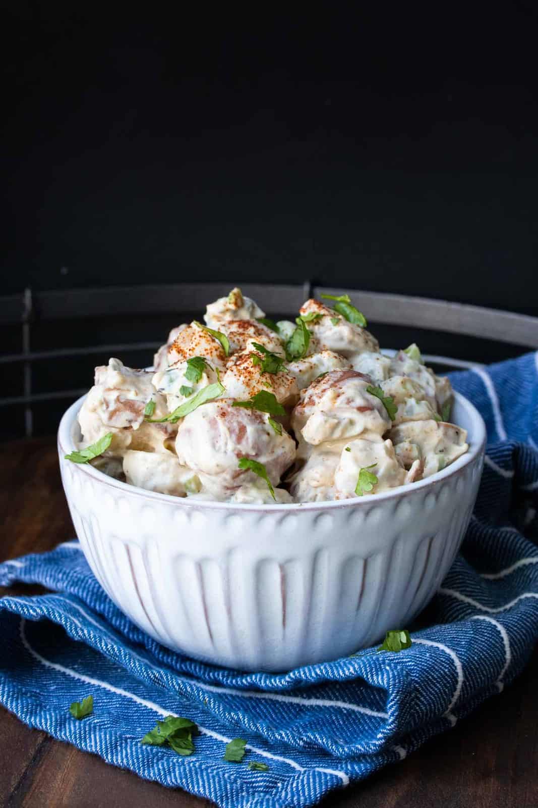 White bowl filled with creamy potato salad on a blue napkin