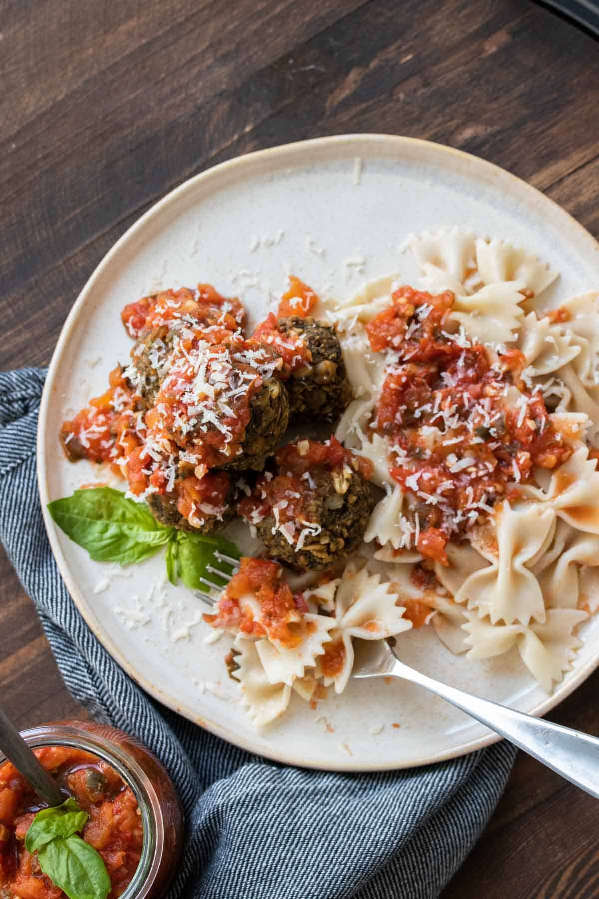 Fork getting a bite of bowtie pasta and marinara from a cream plate