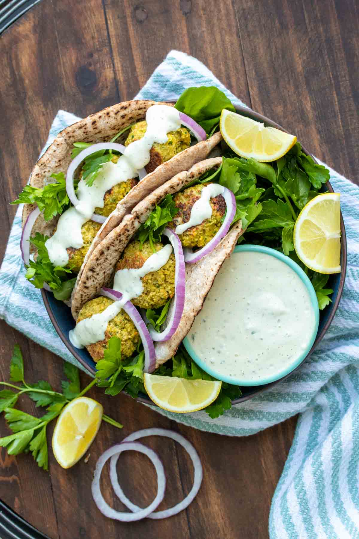 Two falafel pita sandwiches on a plate next to ranch dip