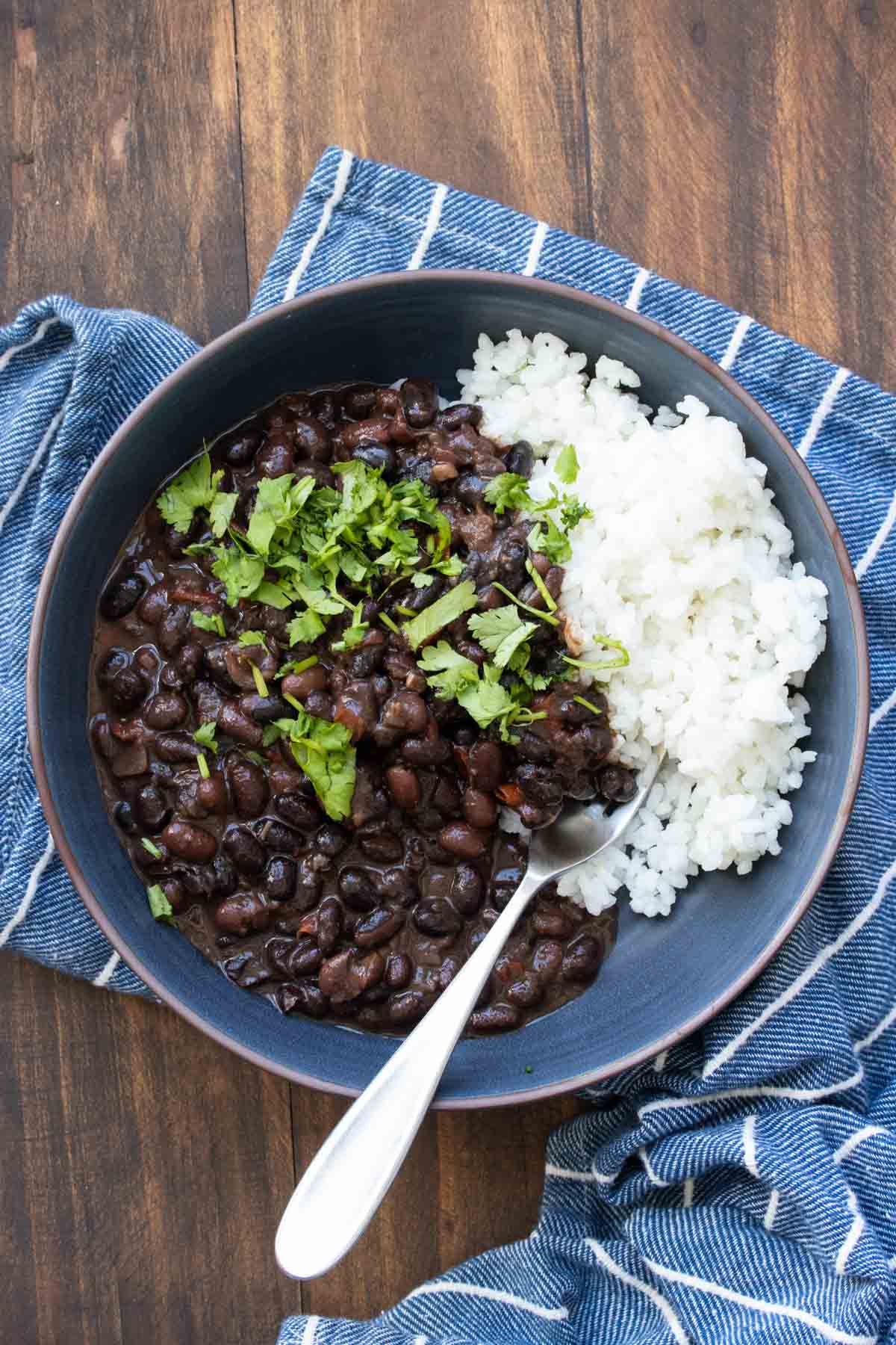 Blue bowl with cooked black beans over white rice