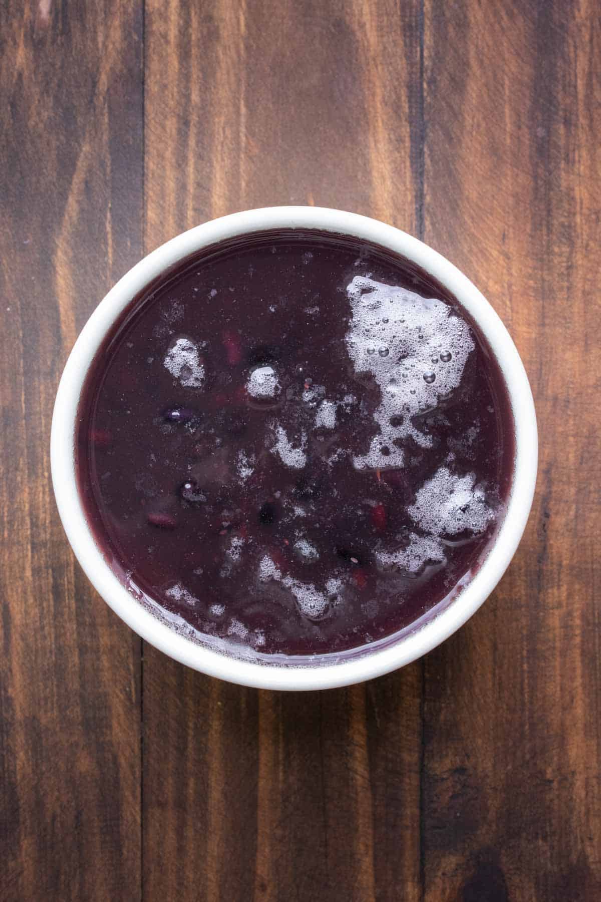 Dried black beans soaking in water in a white bowl.