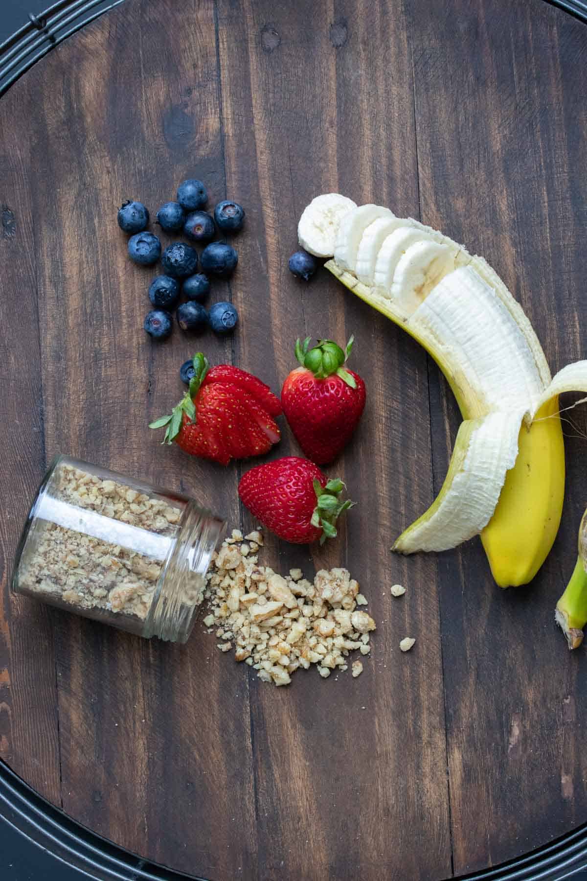 Looking for the perfect way to start your day? This vegan oatmeal recipe is the ultimate creamy delicious choice and it comes together in mere minutes! #veganbreakfastrecipes #easymeals Fruit and nuts to top oatmeal with on a wooden surface