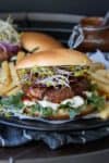 Portobello mushroom burger on a bun with lettuce, sprouts and sauce