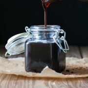 Glass jar filling with poured teriyaki sauce