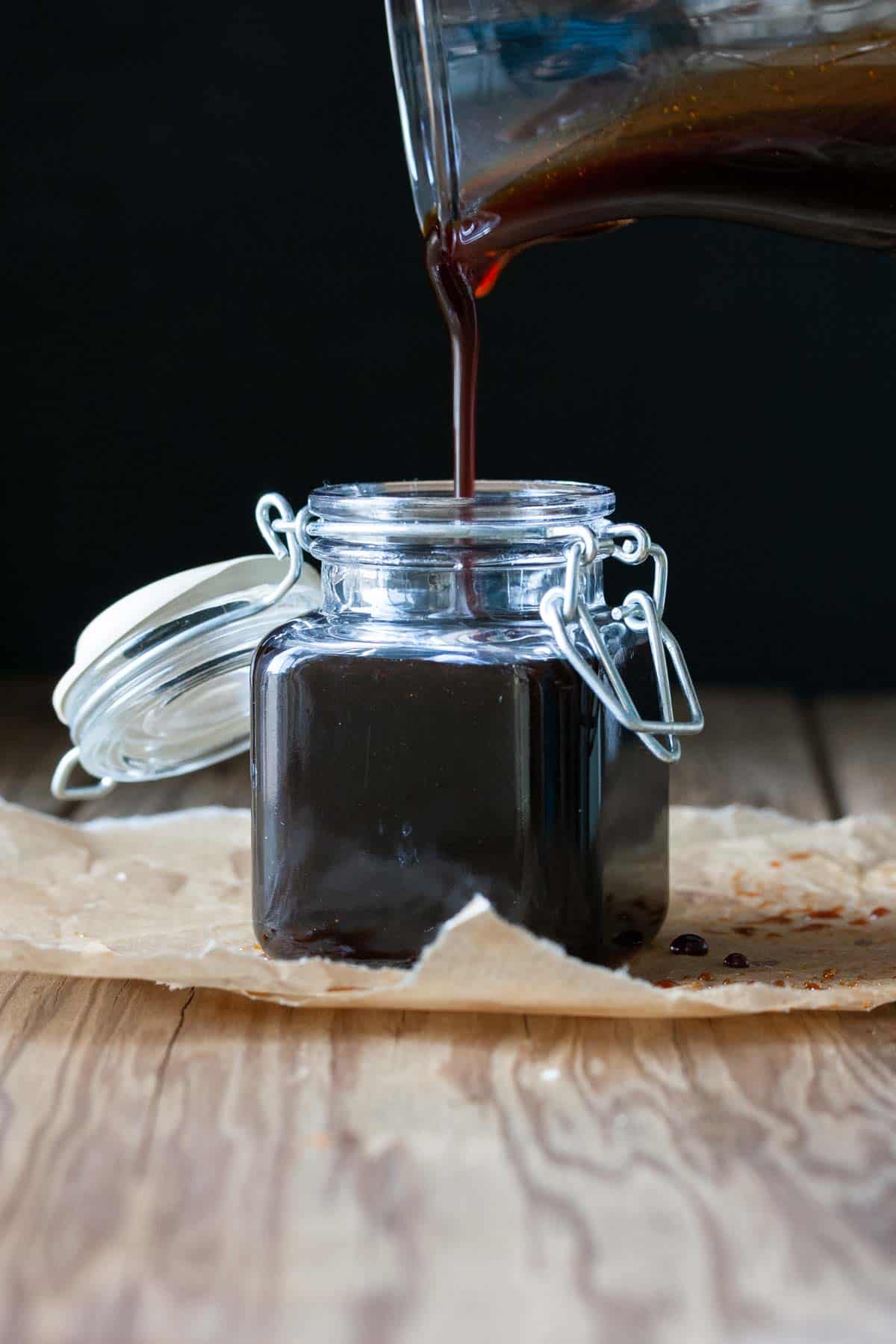 Glass jar filling with poured teriyaki sauce