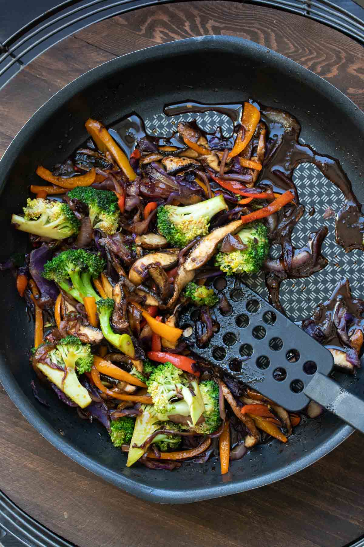 Spatula mixing sliced veggies and teriyaki sauce in a pan