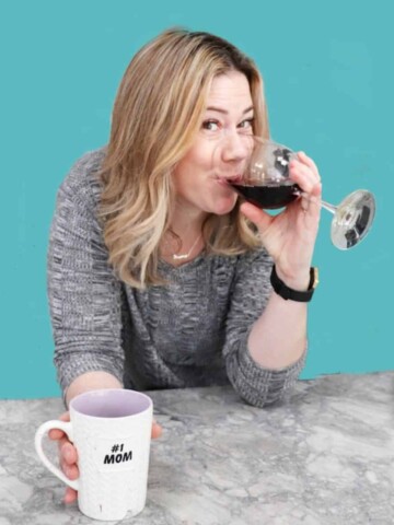 A photo of a mom drinking wine and holding a coffee mug