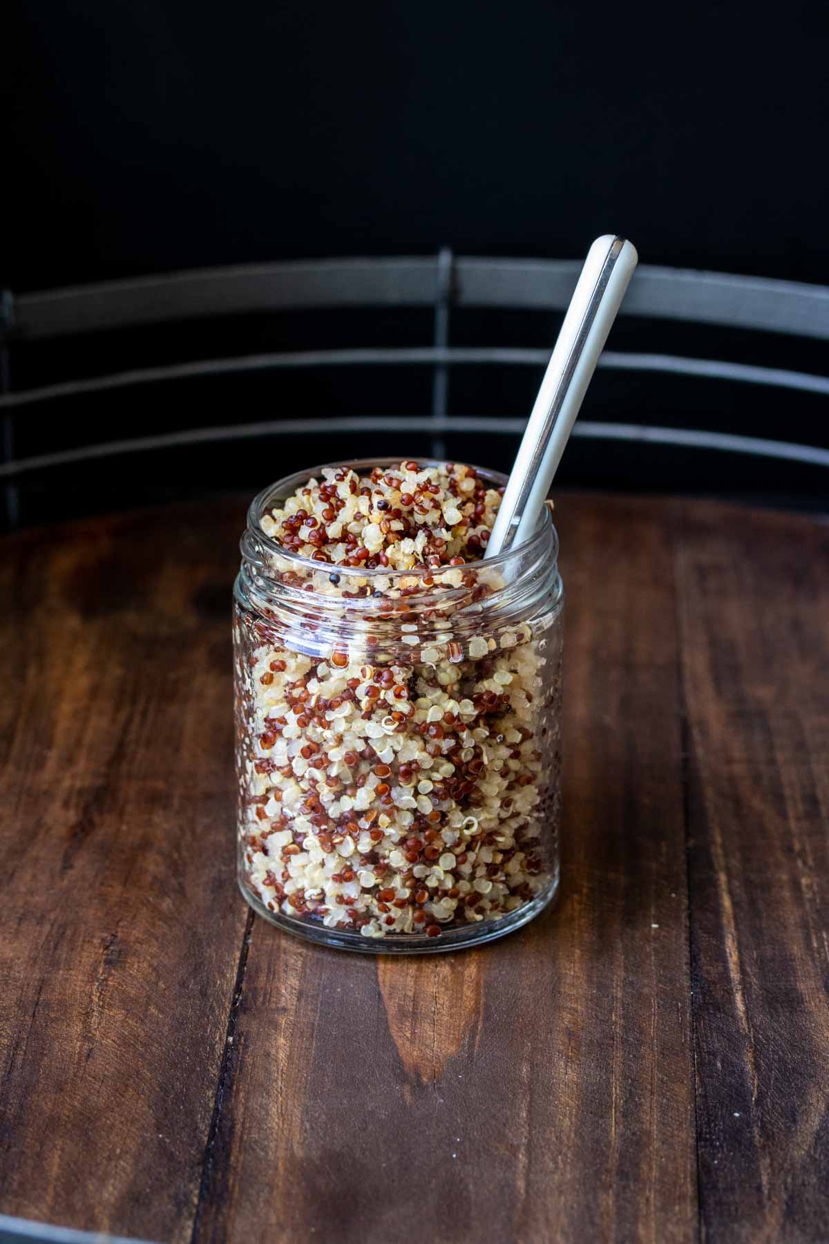 Small glass jar with cooked quinoa and a spoon in it