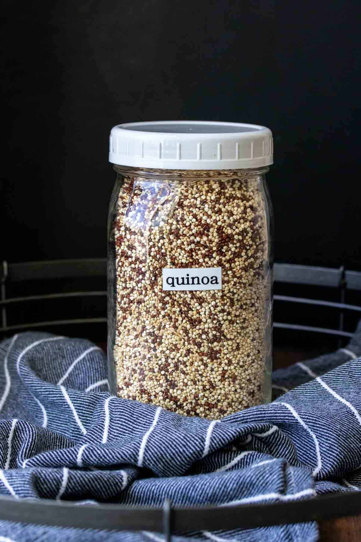 Glass jar with white lid filled with dry quinoa