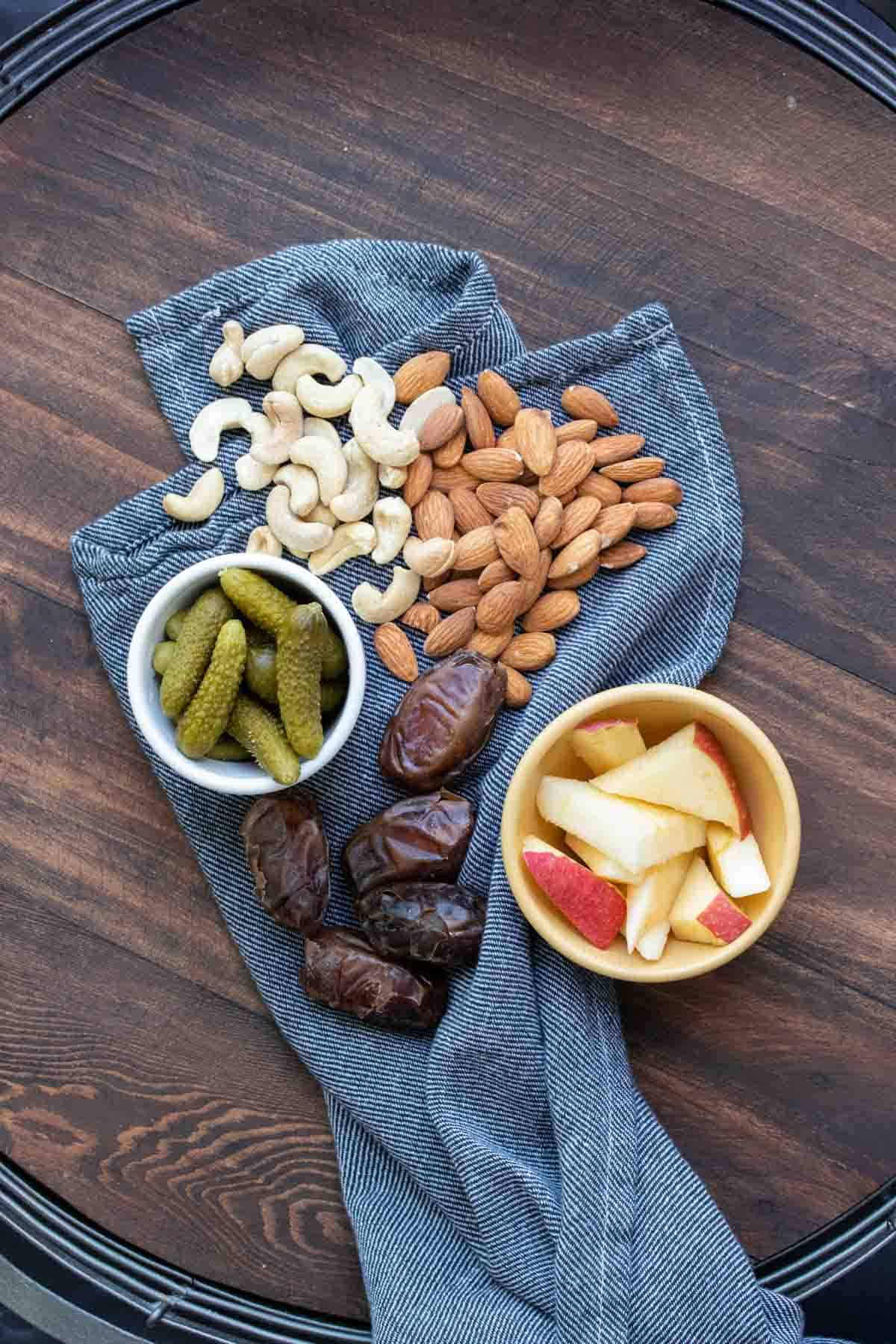 Nuts, pickles and fruit in bowls and laying on a navy towel