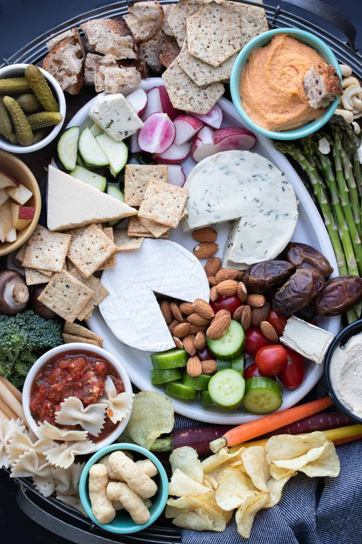 Top view of a large charcuterie spread on a white platter and surrounding it on all sides