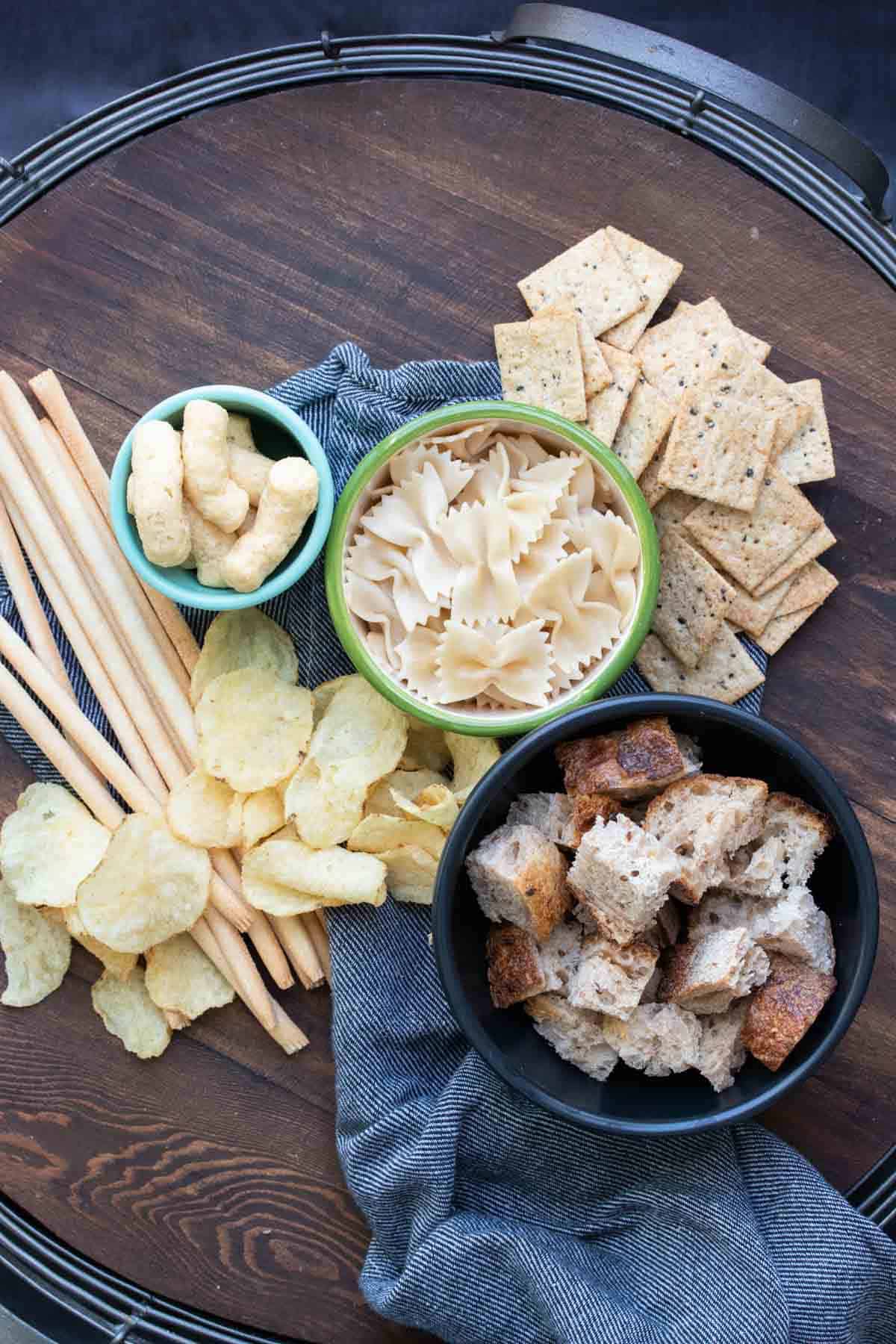 Different kinds of crackers, bread, snacks and pasta in bowls