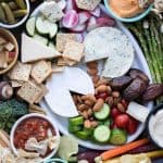 A charcuterie spread on a white platter and around the platter.