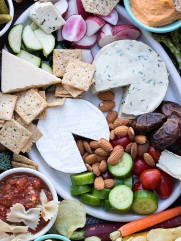 A charcuterie spread on a white platter and around the platter.