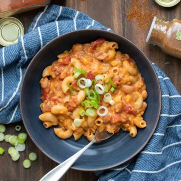 Top view of a black bowl filled with chili mac and cheese and a fork in it