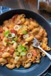 Fork getting a bite of chili mac and cheese in a black bowl