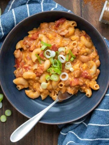 Black bowl filled with chili mac and cheese sitting on a navy blue towel