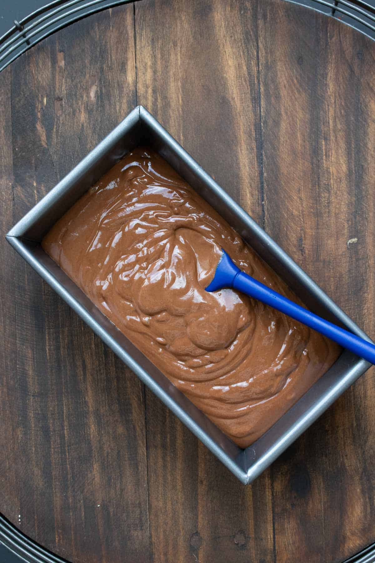 A spatula putting chocolate ice cream base into a rectangular pan