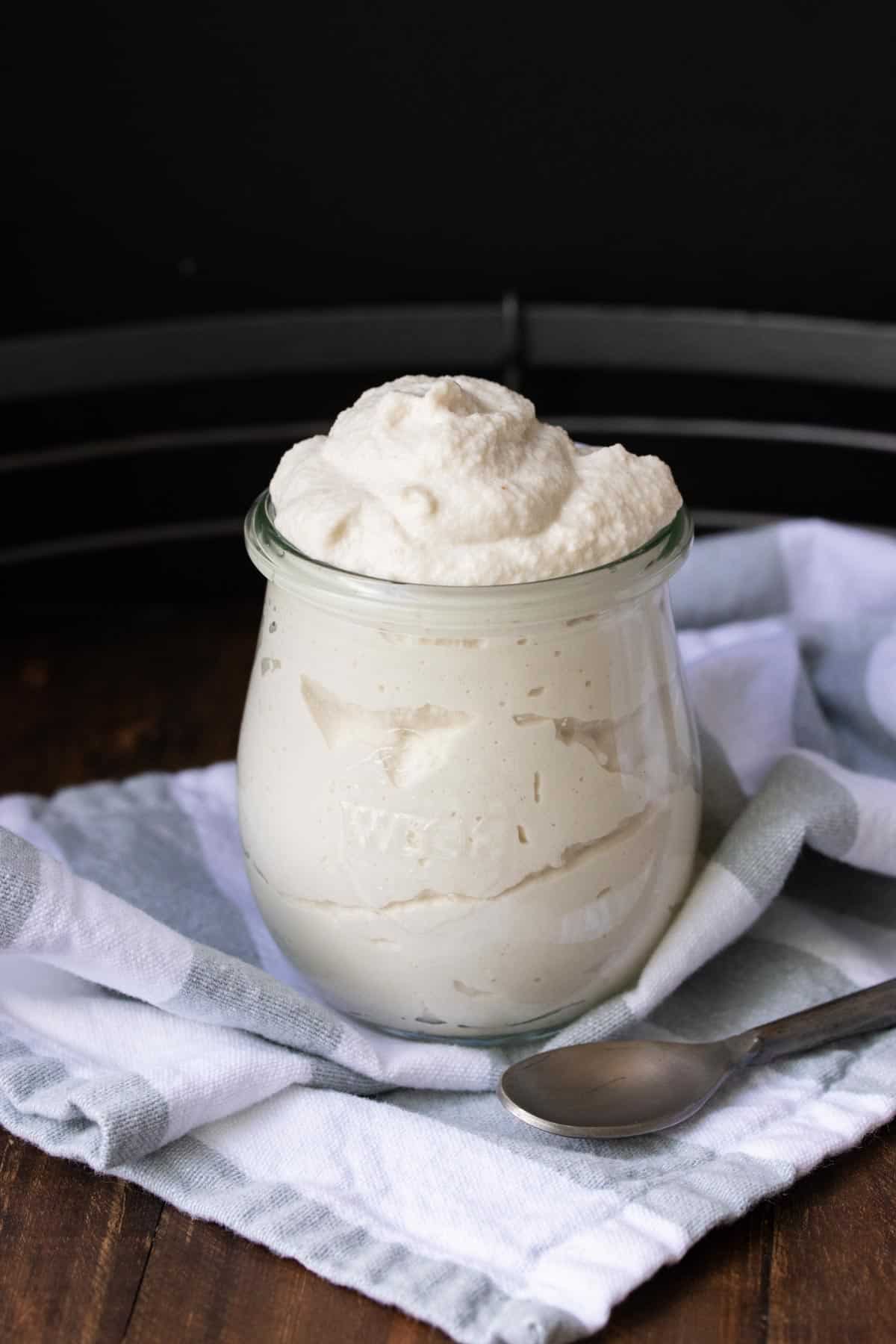 A glass jar filled with mascarpone cheese sitting on a striped towel