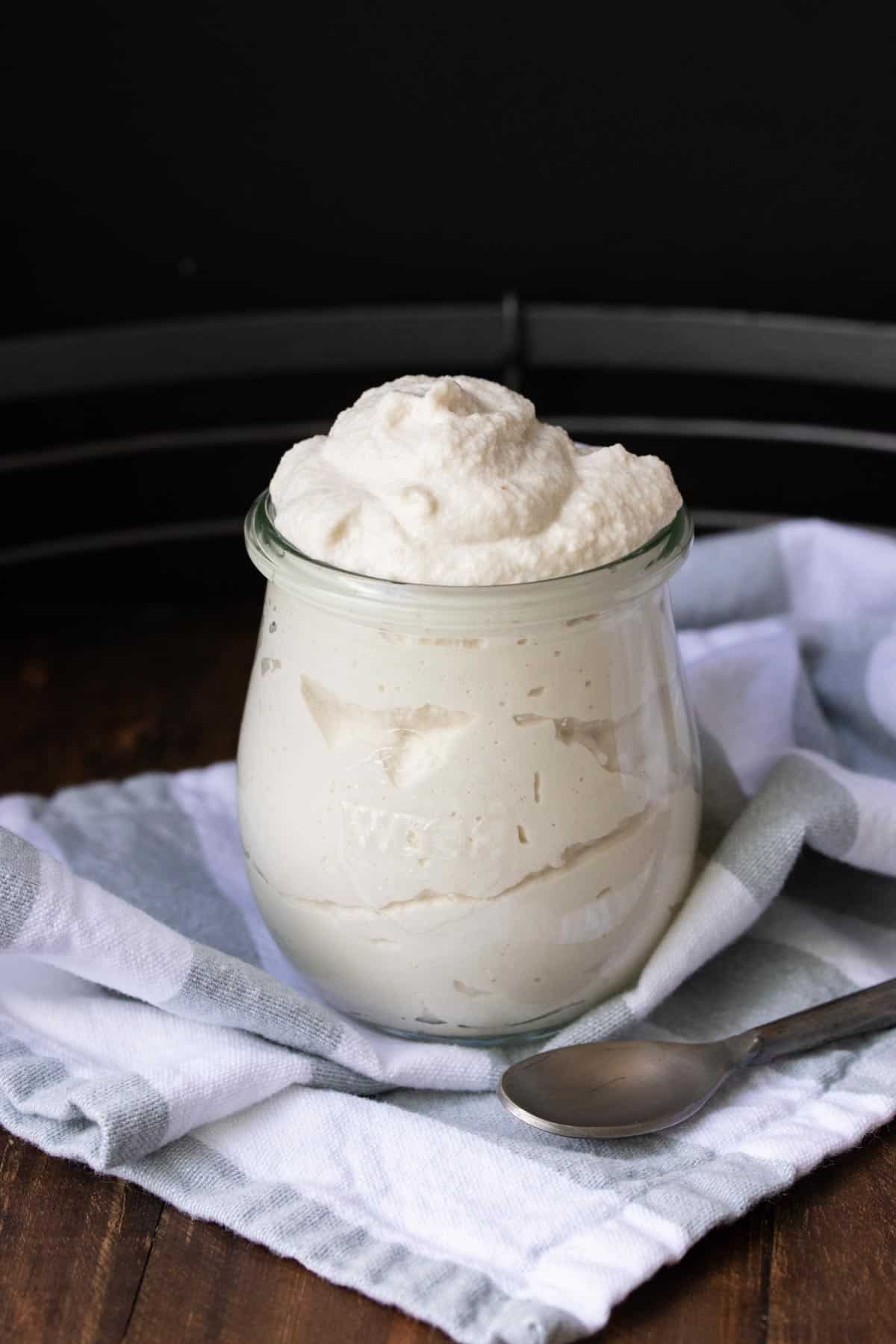 A glass jar filled with mascarpone cheese sitting on a striped towel.