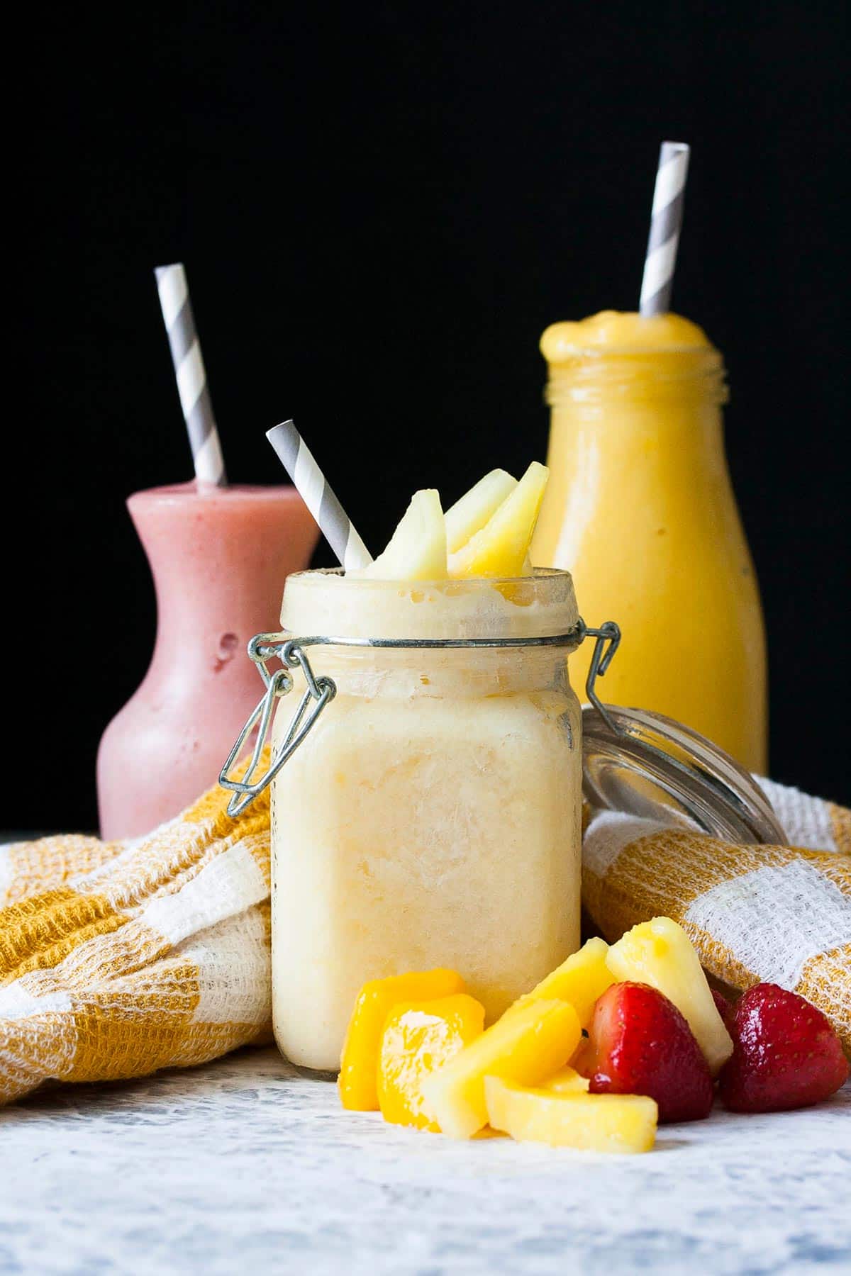 Three different glass jars filled with different colored fruit smoothies