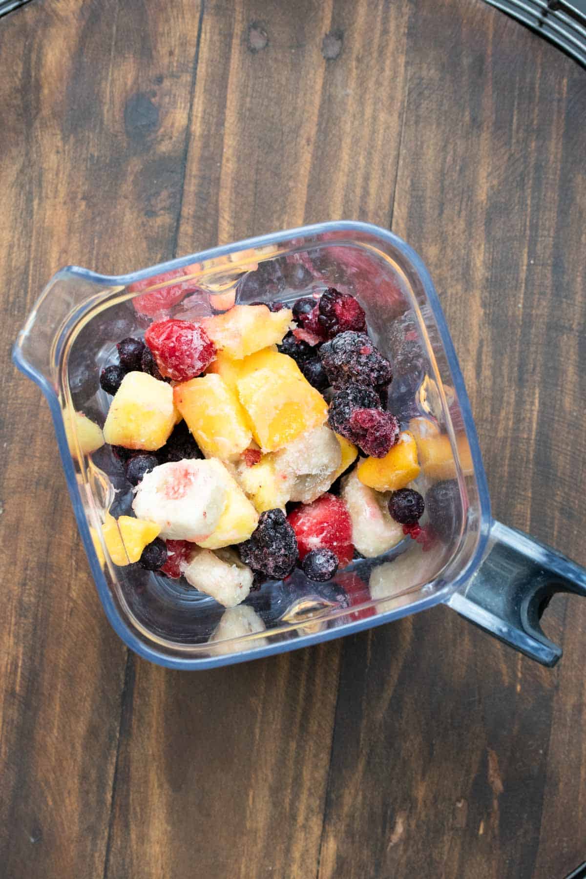 Top view of frozen fruit in a blender.