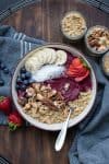 Un smoothie bowl en un bol de crema coronado con fruta y frutos secos