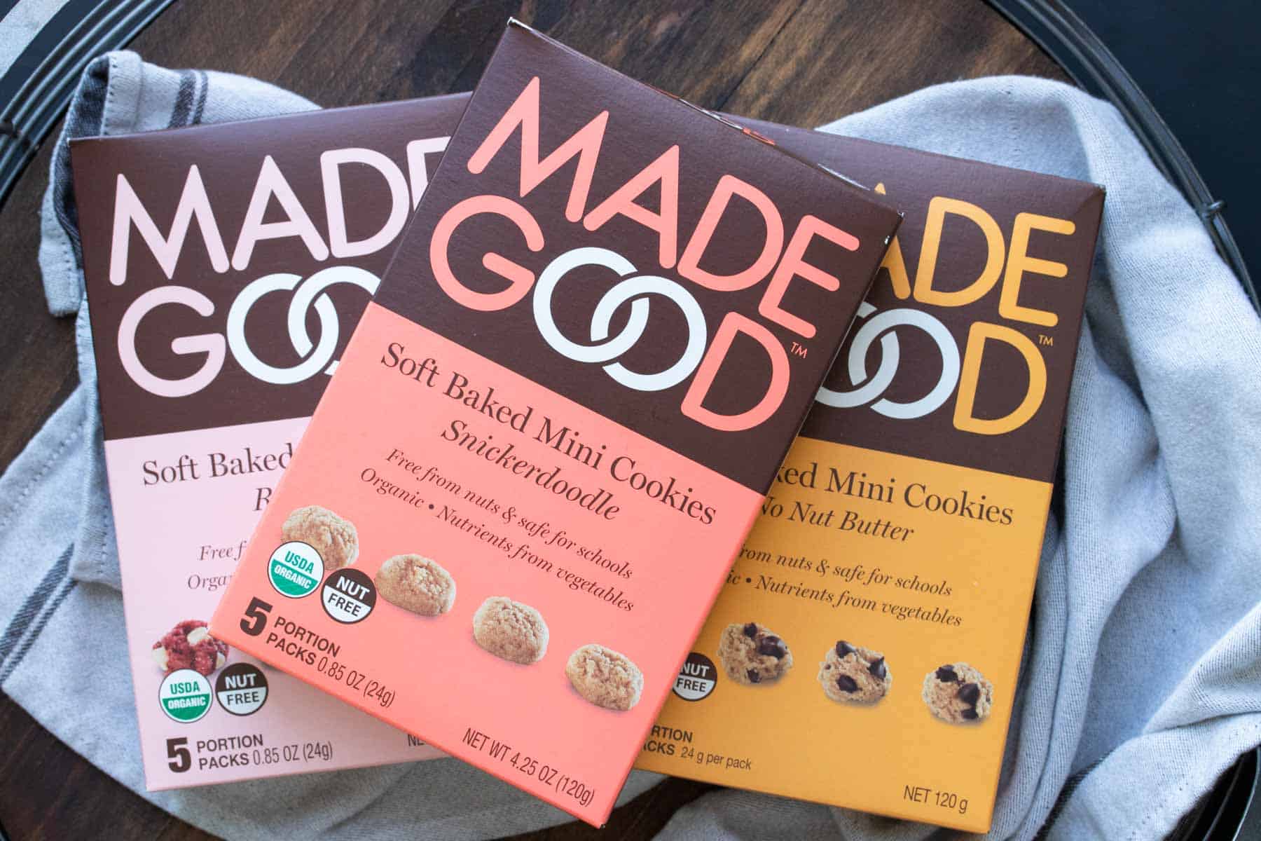 Three boxes of Made Good brand soft mini cookies inside sitting on a towel