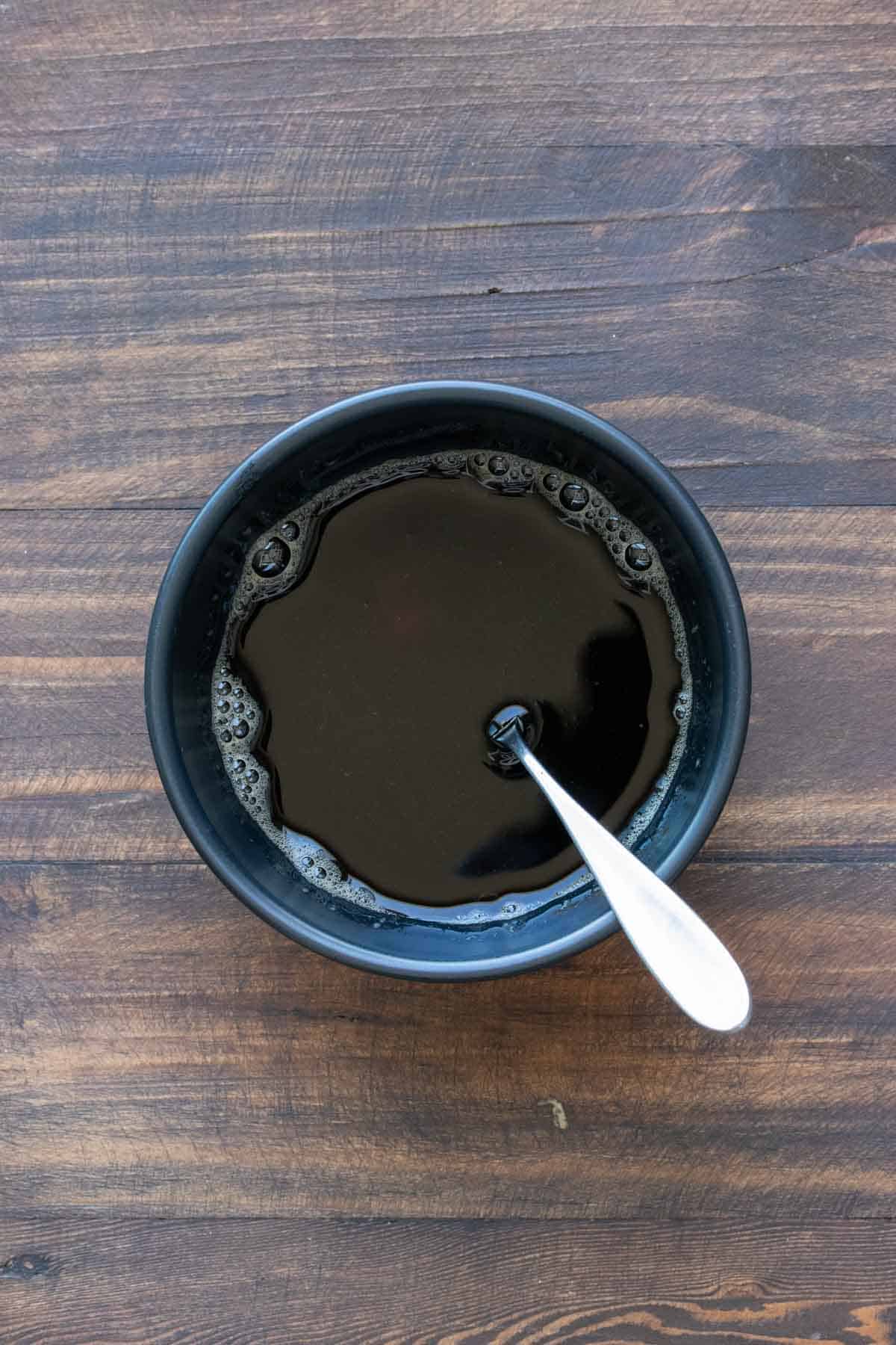 Spoon in a black bowl filled with coffee