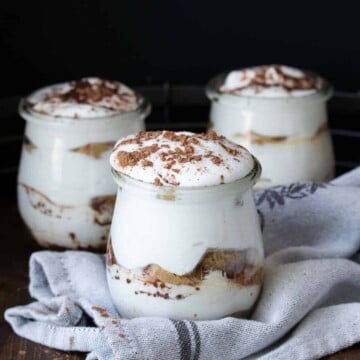 Three glass jars of tiramisu sitting on a grey towel