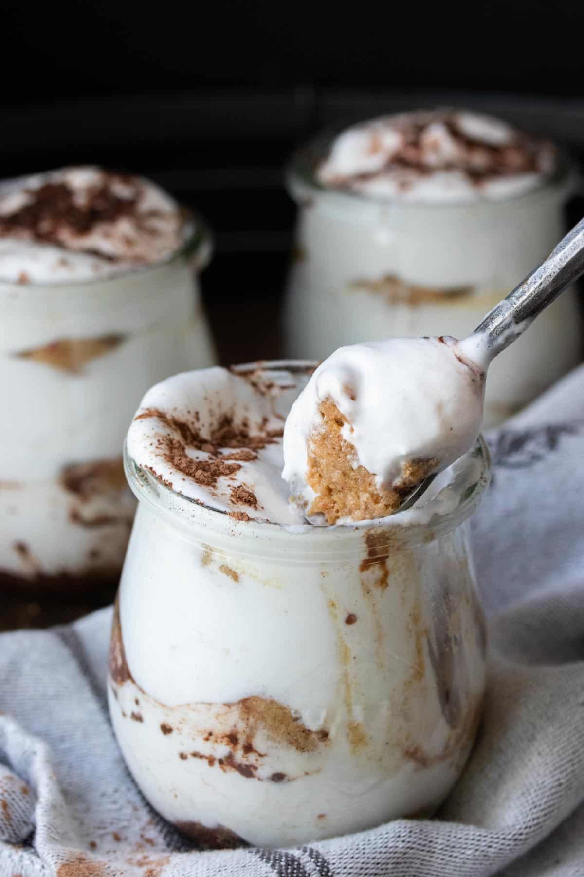 Spoon getting a bite of Tiramisu from a glass jar