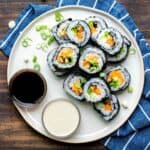 Veggie sushi rolls cut up and piled on a cream plate