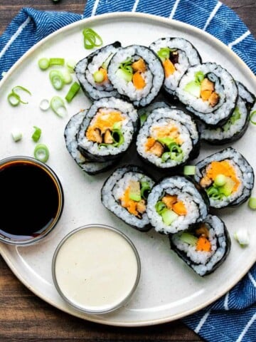 Veggie sushi rolls cut up and piled on a cream plate