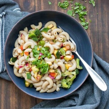 Top view of a black bowl filled with vegetable pasta salad