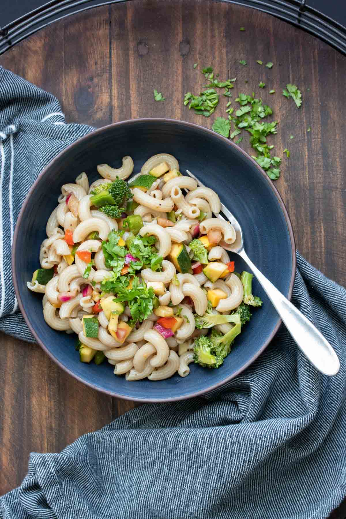 Top view of a black bowl filled with vegetable pasta salad