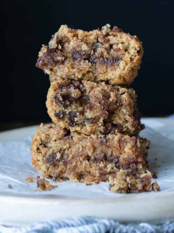 A photo of three chocolate chip blondies piled up on a plate