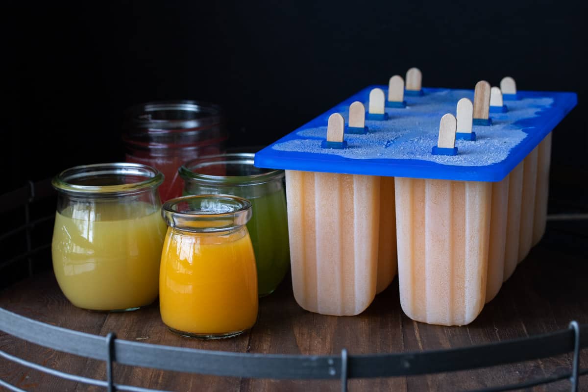 Glass jars with juices next to a popsicle mold