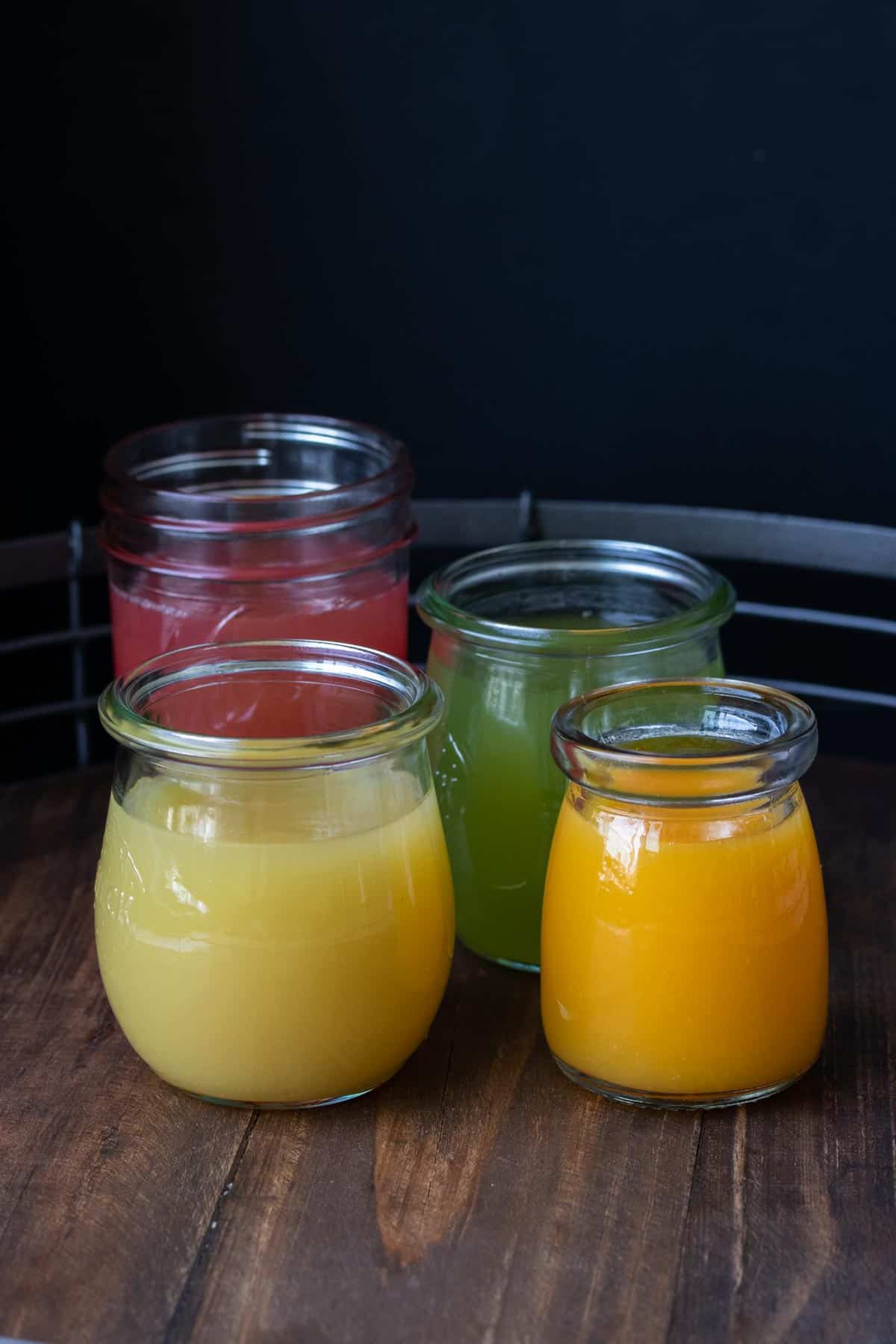 Four glass jars on a table filled with different juices