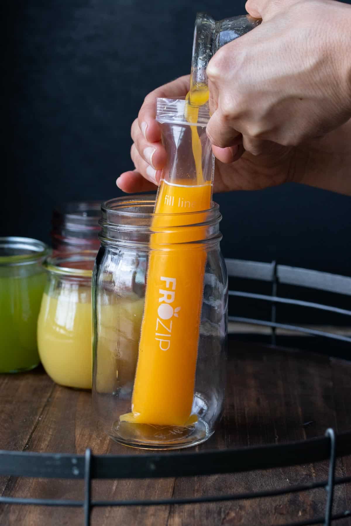 Hand pouring orange juice into a popsicle bad