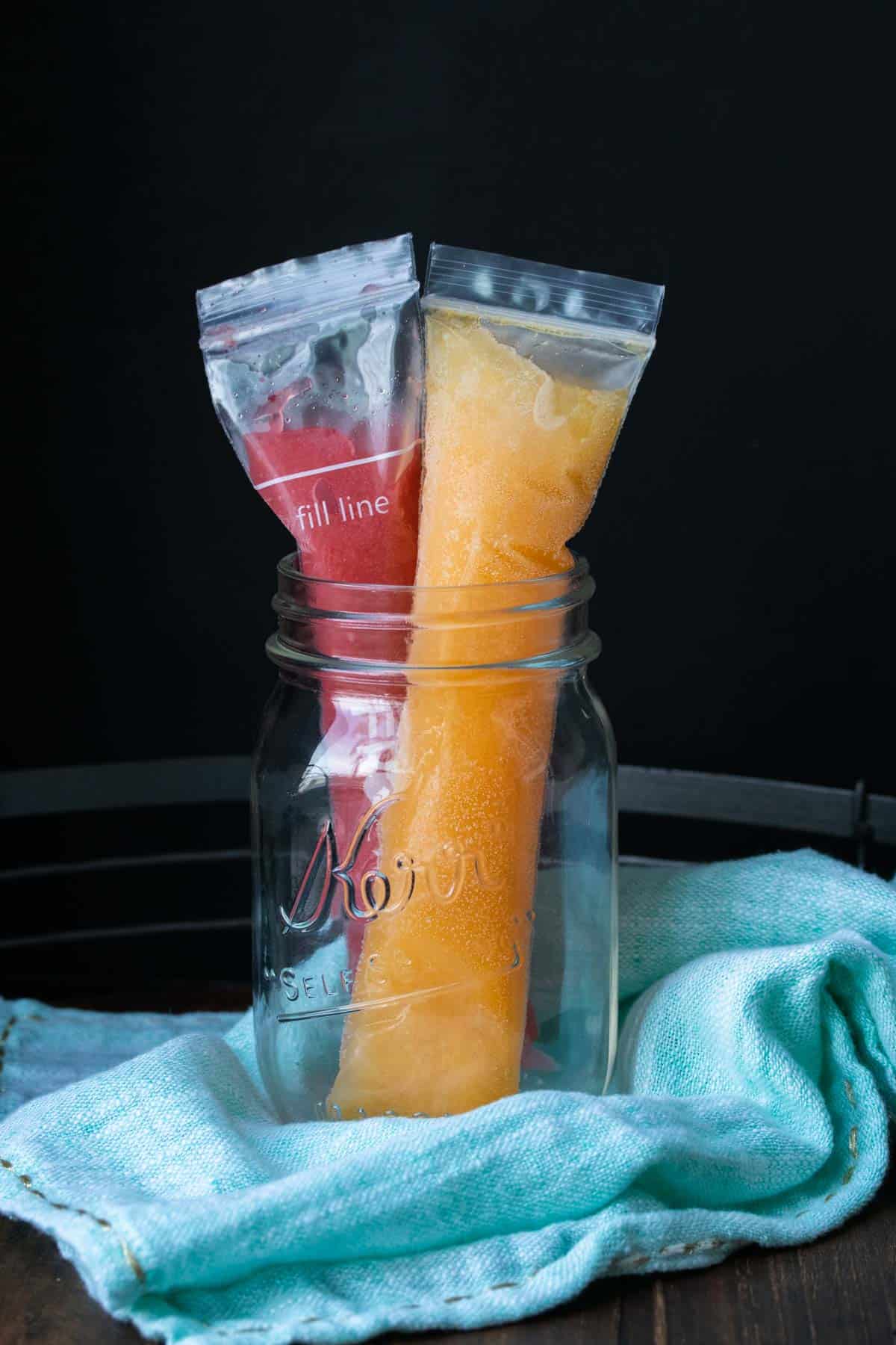 Two frozen skinny ice pops in a glass jar