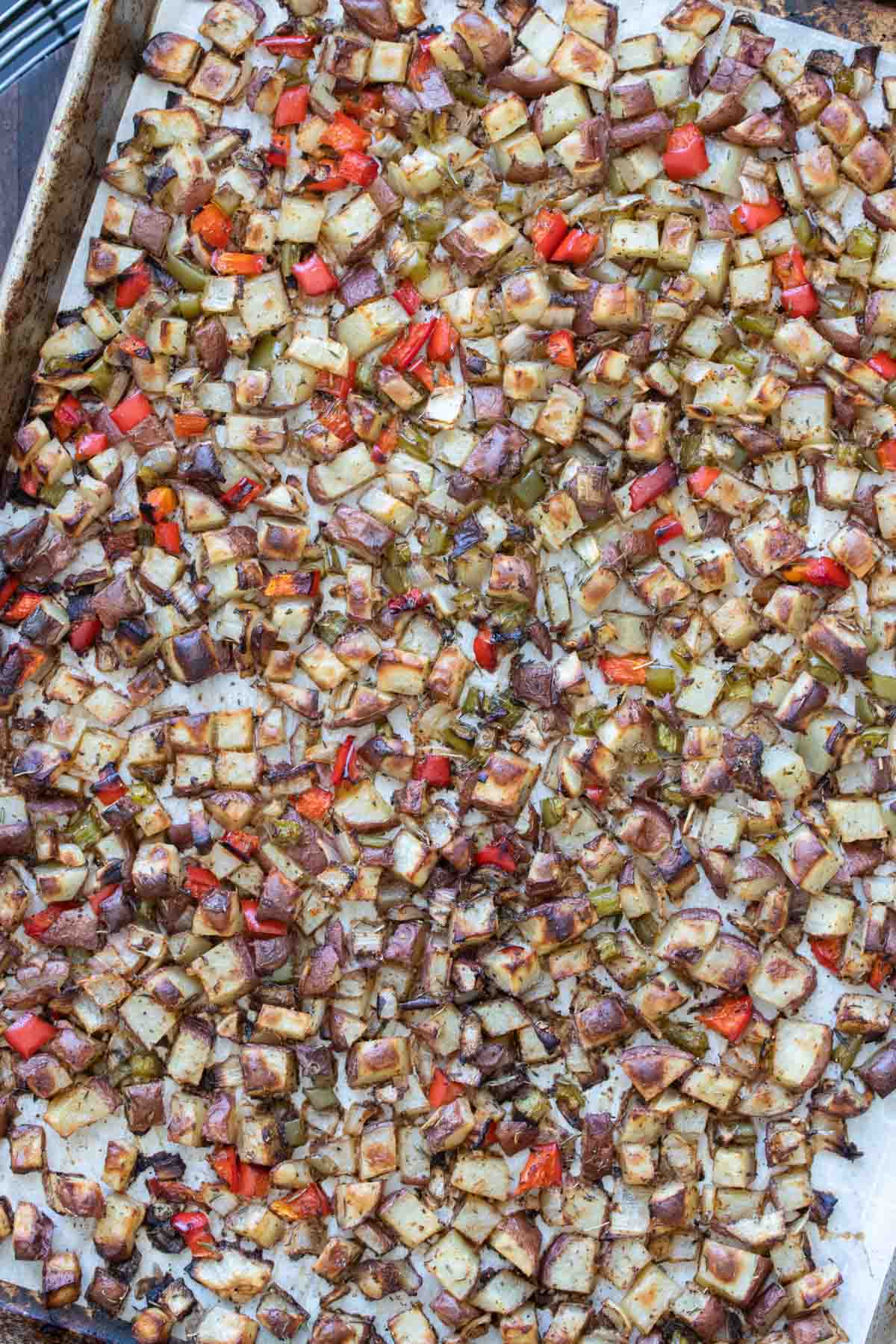 Baking sheet filled with roasted chopped potatoes, peppers and onions