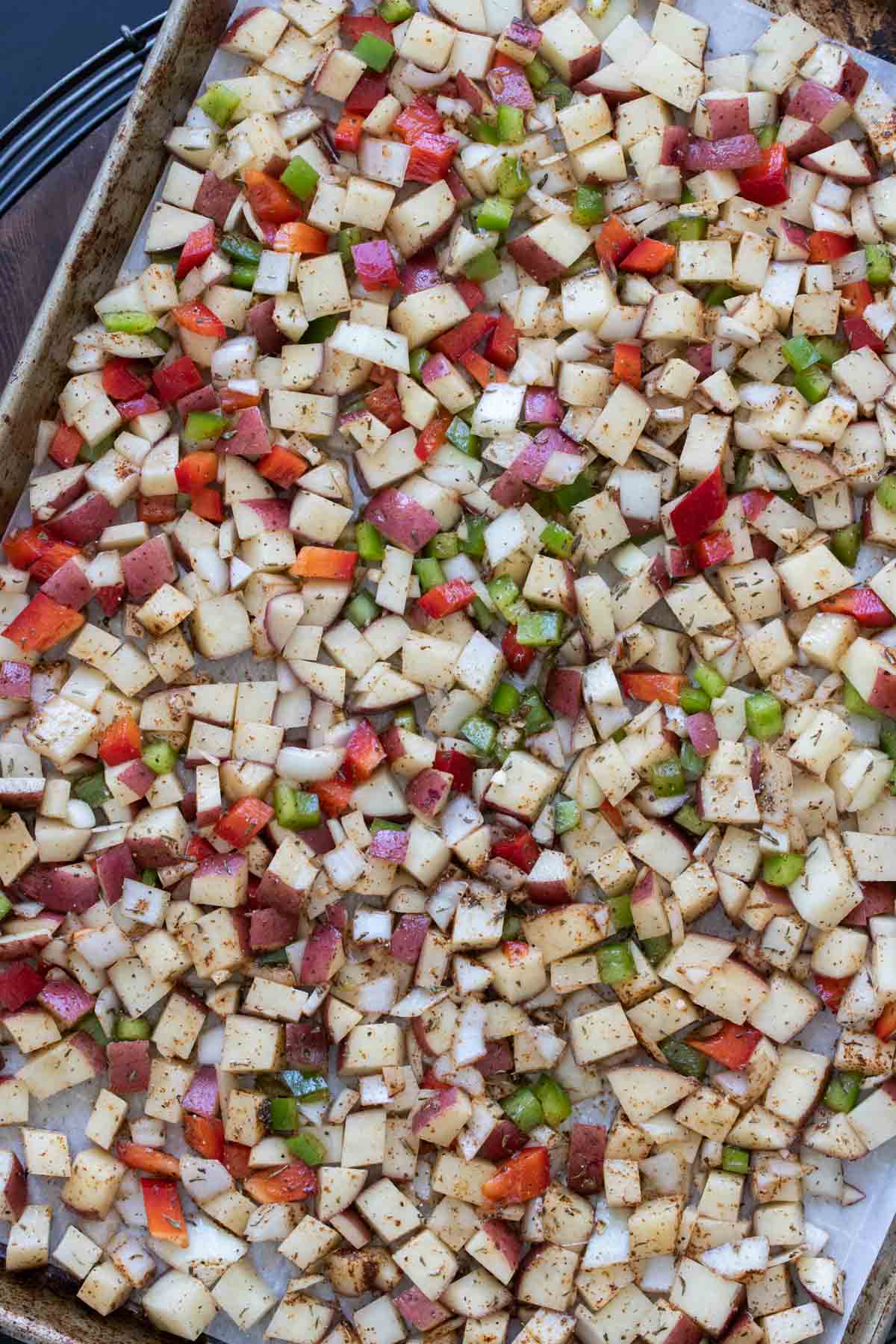 Chopped potatoes, onions and peppers on a baking sheet