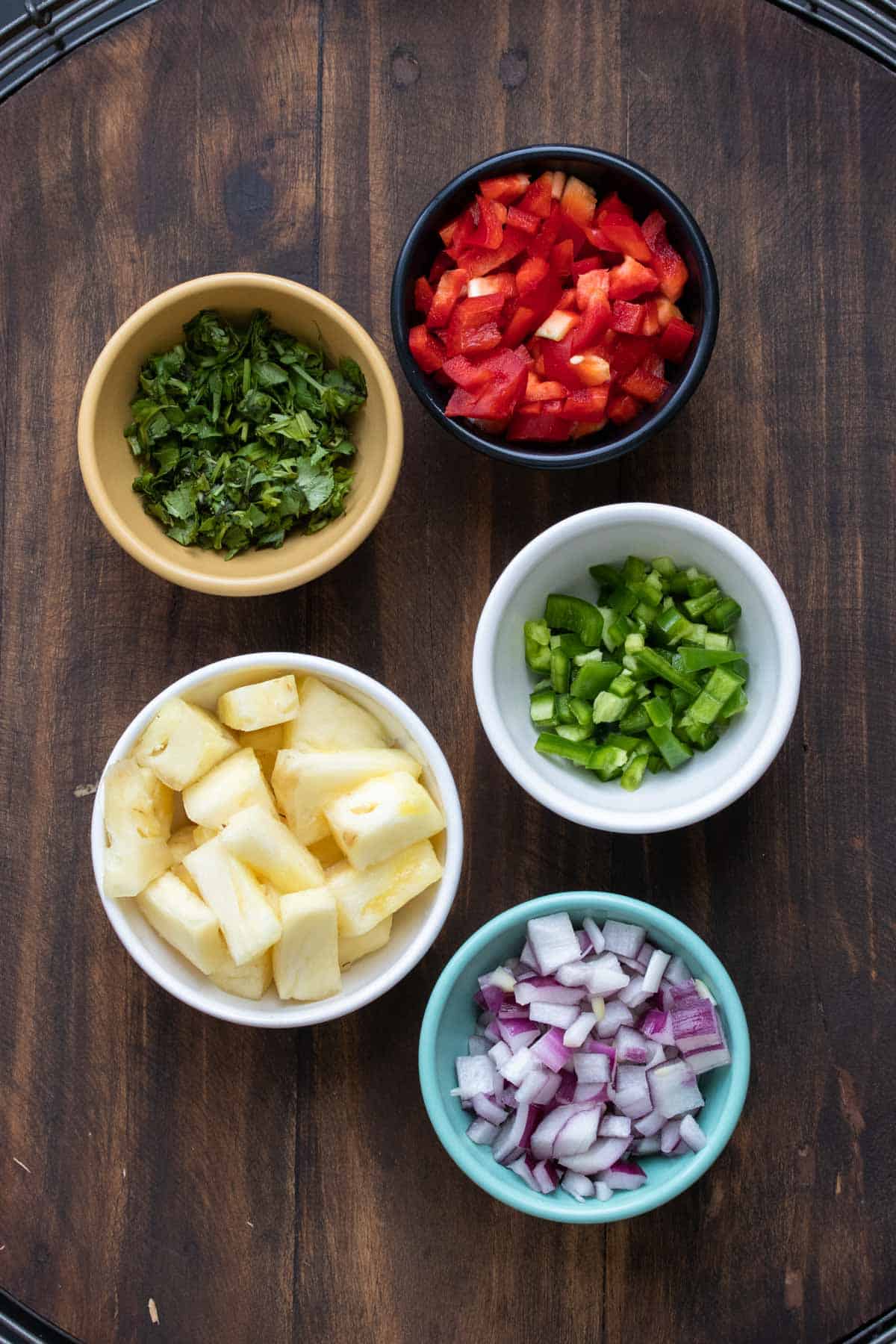 Top view of bowls of pineapple salsa ingredients
