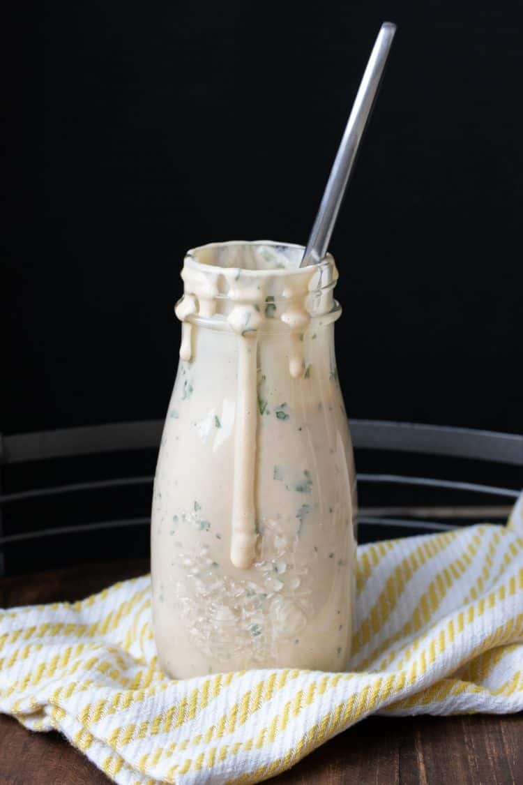 Glass jar filled with a peach colored creamy sauce dripping off the side