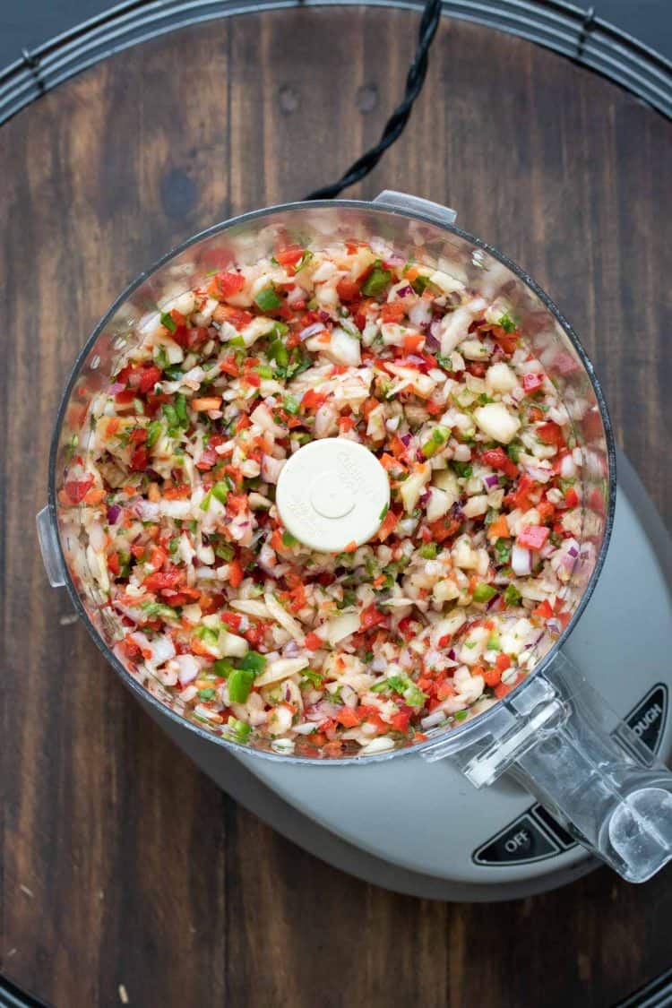 Top view of food processor with chopped pineapple salsa inside