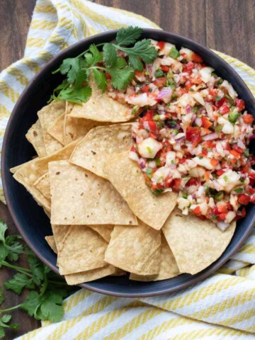 Pile of tortilla chips in a bowl next to pineapple salsa