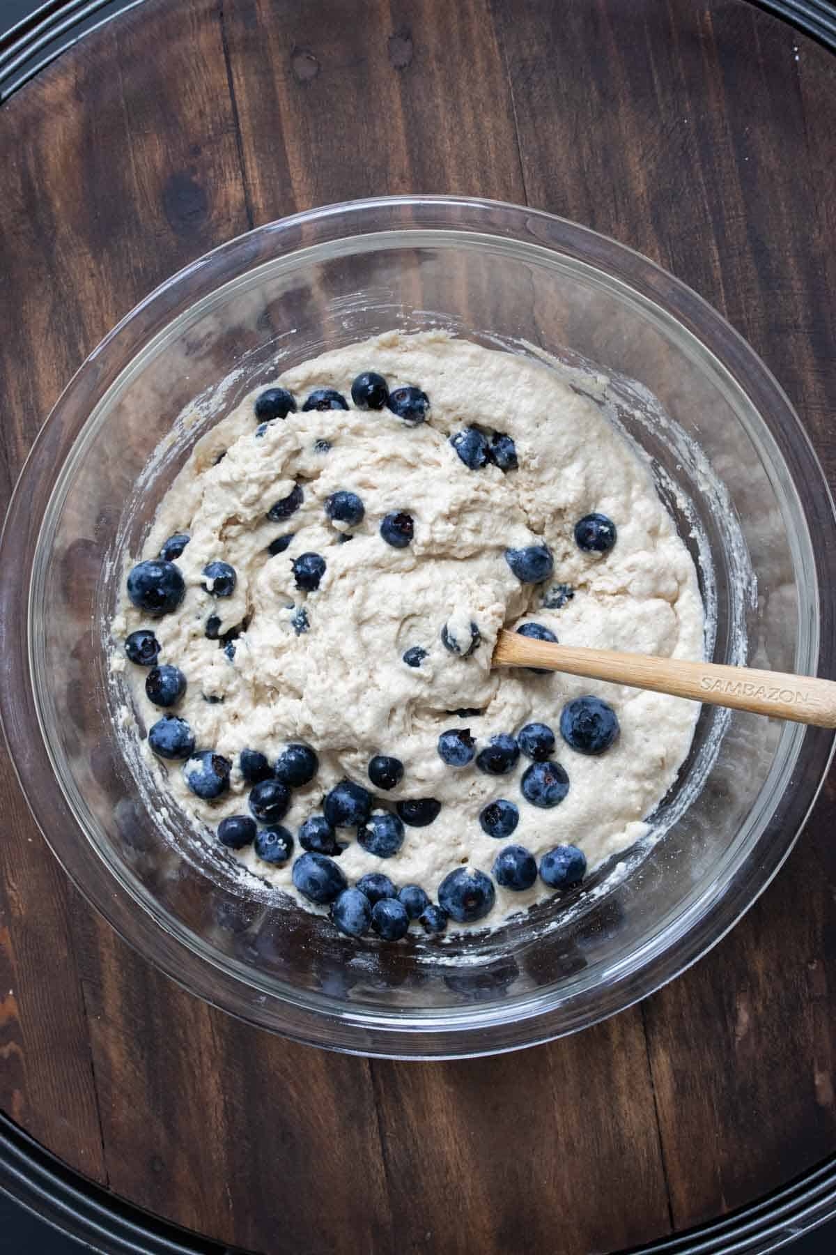 Top view of pancake batter with blueberries in a glass bowl.