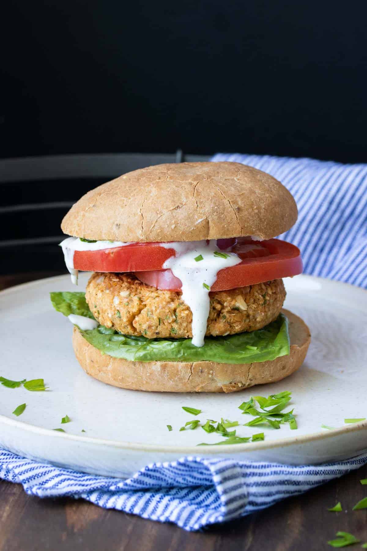 Chickpea burger on a bun with lettuce tomato and sauce dripping