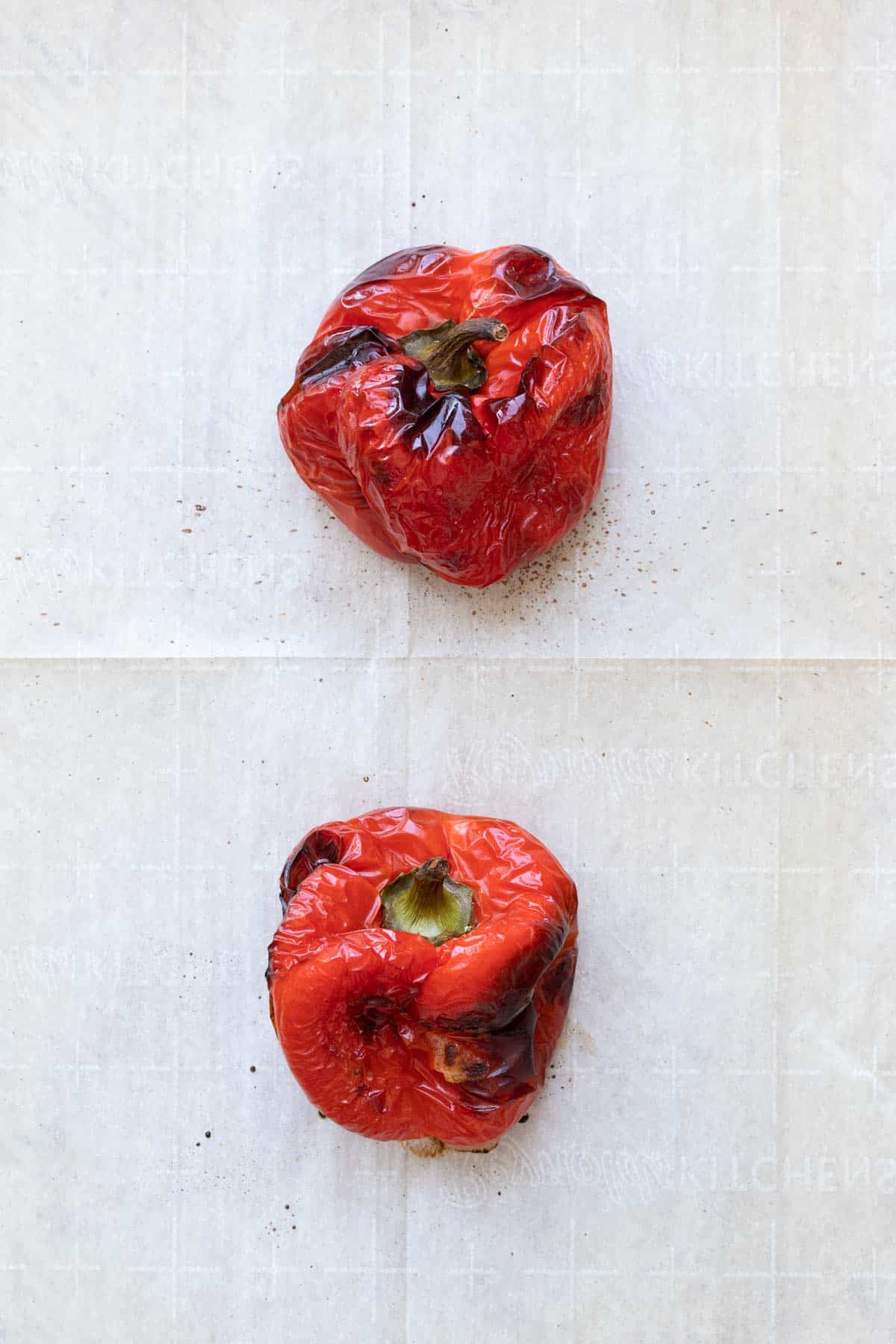 Two roasted red peppers on parchment paper